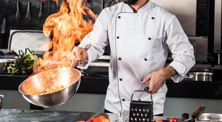 Chef flambéing a dish in a professional kitchen