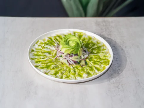 Ceviche with avocado and herbs on a white plate