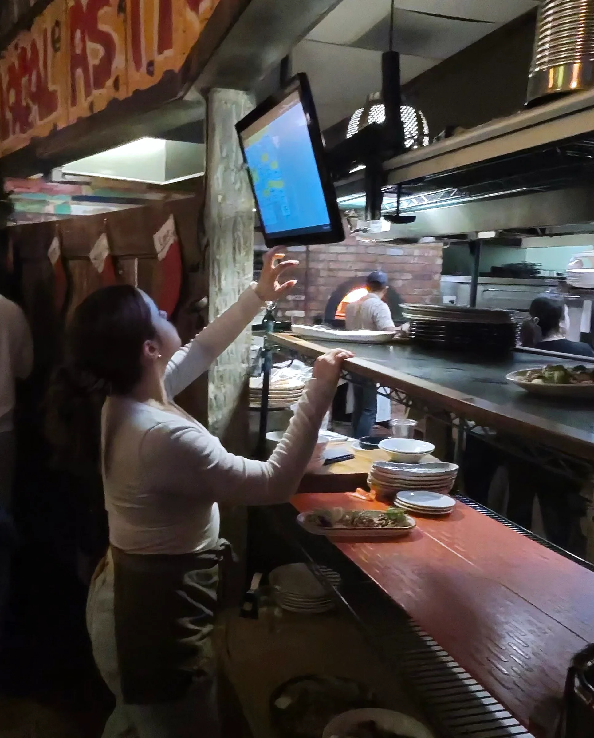 Busy restaurant kitchen with staff and digital order screen