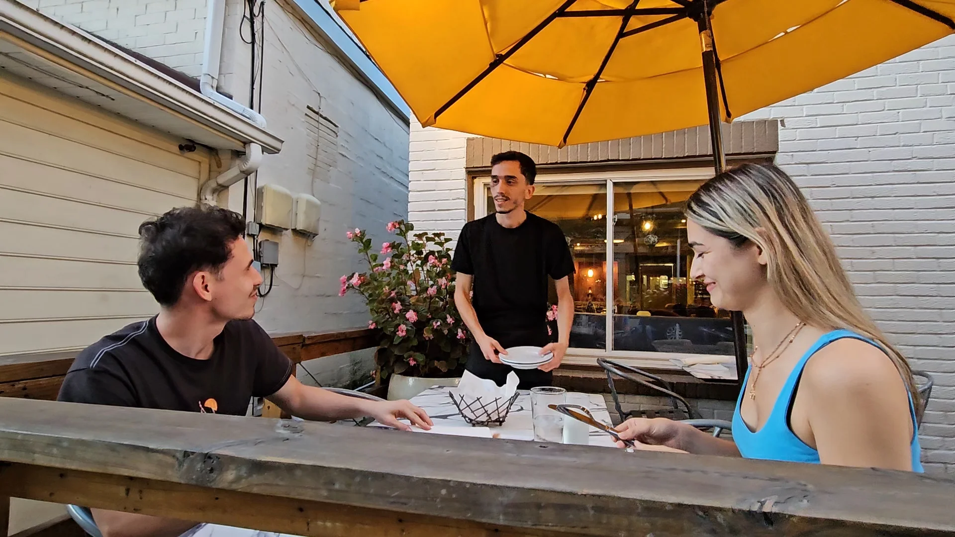 a waiter takes an order as guests enjoy the outdoor patio seating