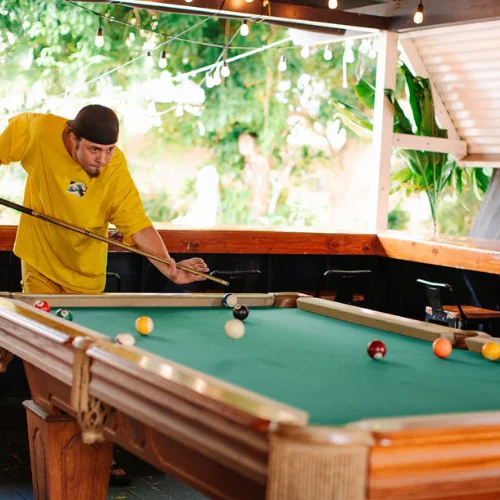 Player enjoying a game of pool in a vibrant outdoor setting