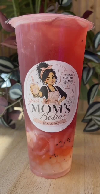 A vibrant drink with a rich red color and tapioca pearls at the bottom, displayed in a clear cup adorned with an eye-catching label.