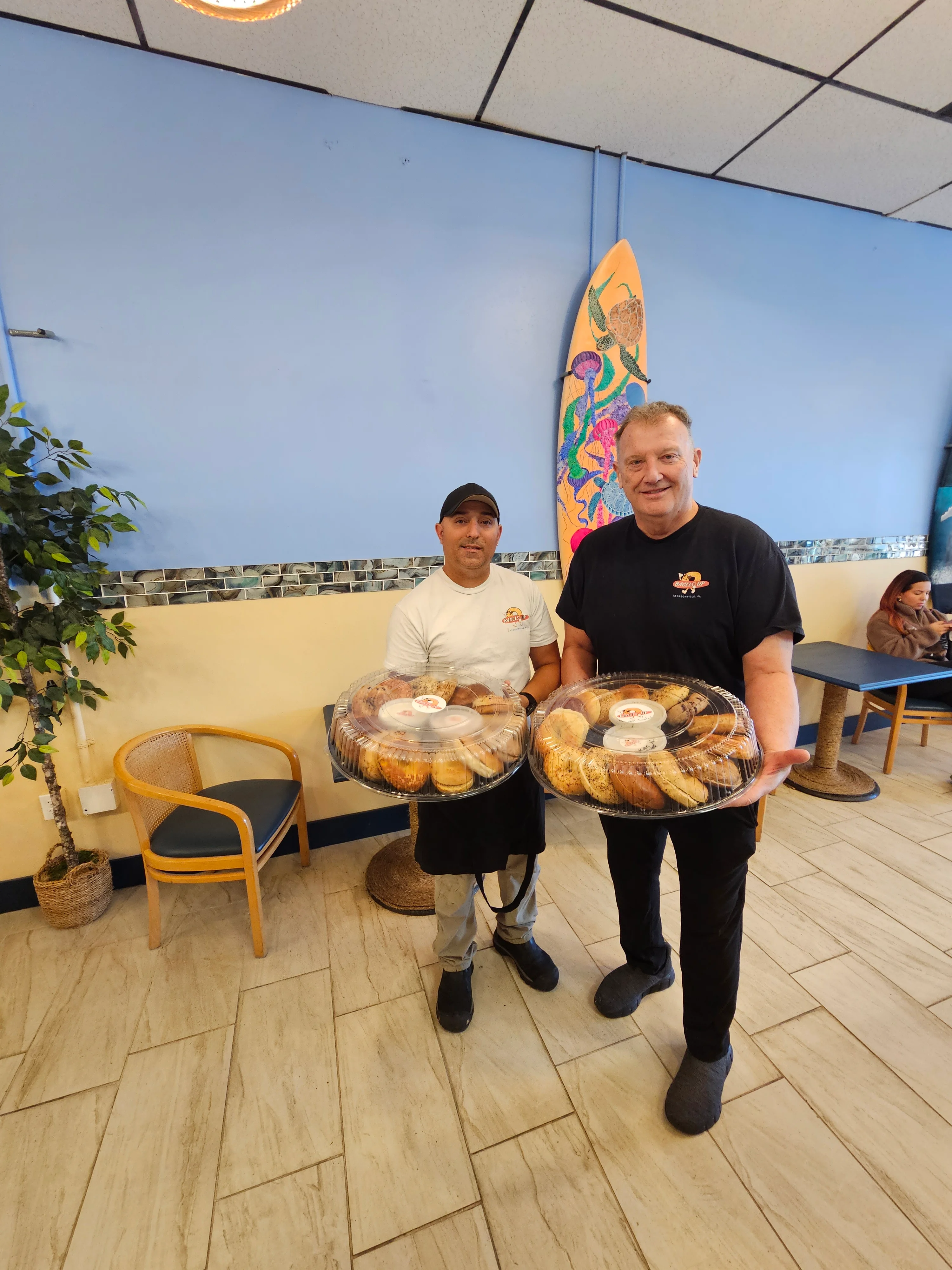 Two chefs holding trays of assorted pastries in a cozy restaurant
