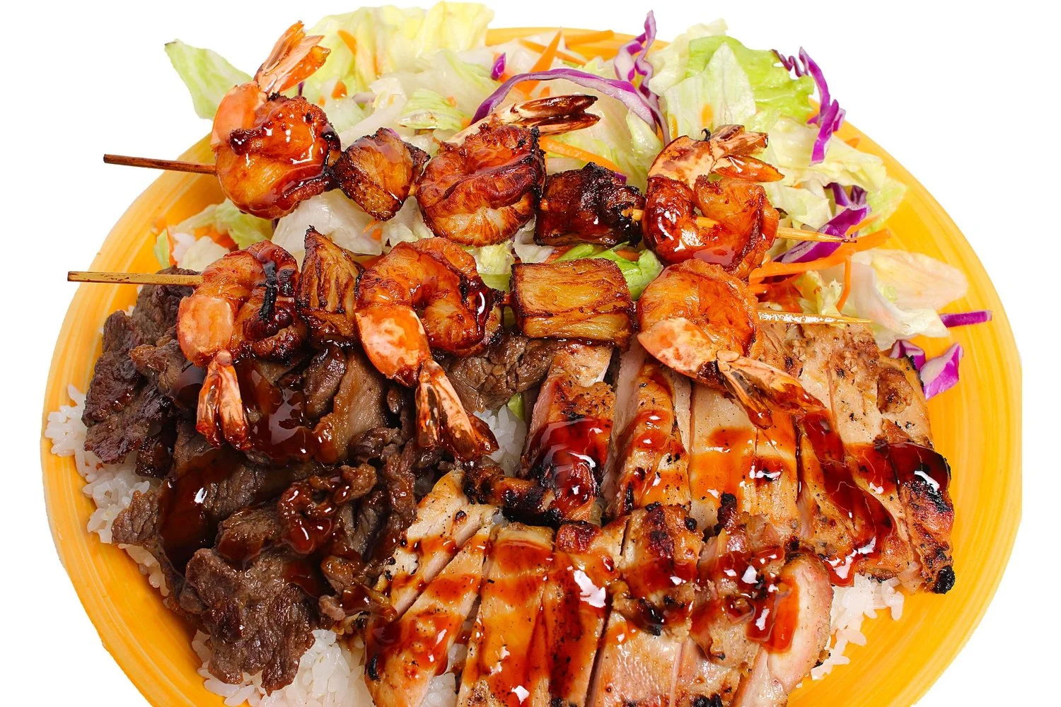 A hearty plate featuring grilled meats topped with shrimp and a BBQ glaze, served over a bed of lettuce.