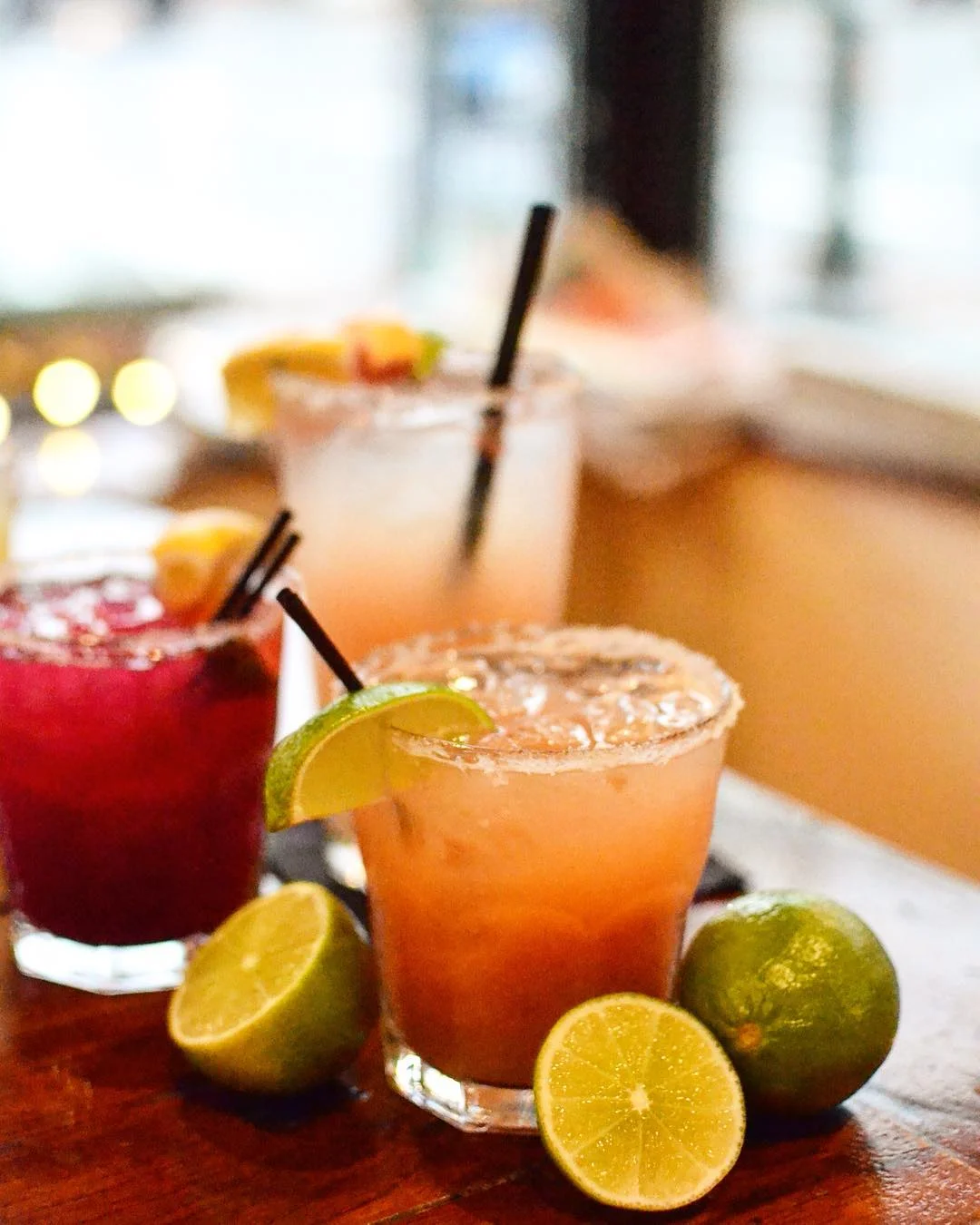 Colorful margaritas with lime and citrus on a wooden bar