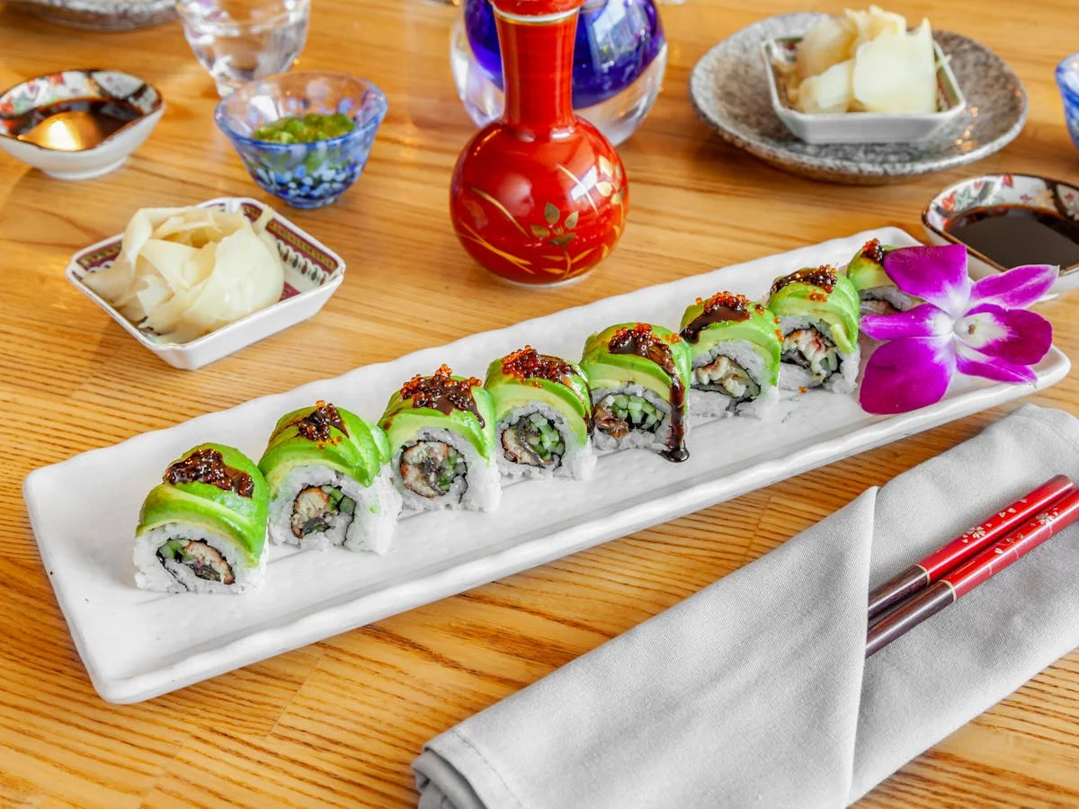 Colorful sushi rolls with avocado and garnishes on a white plate