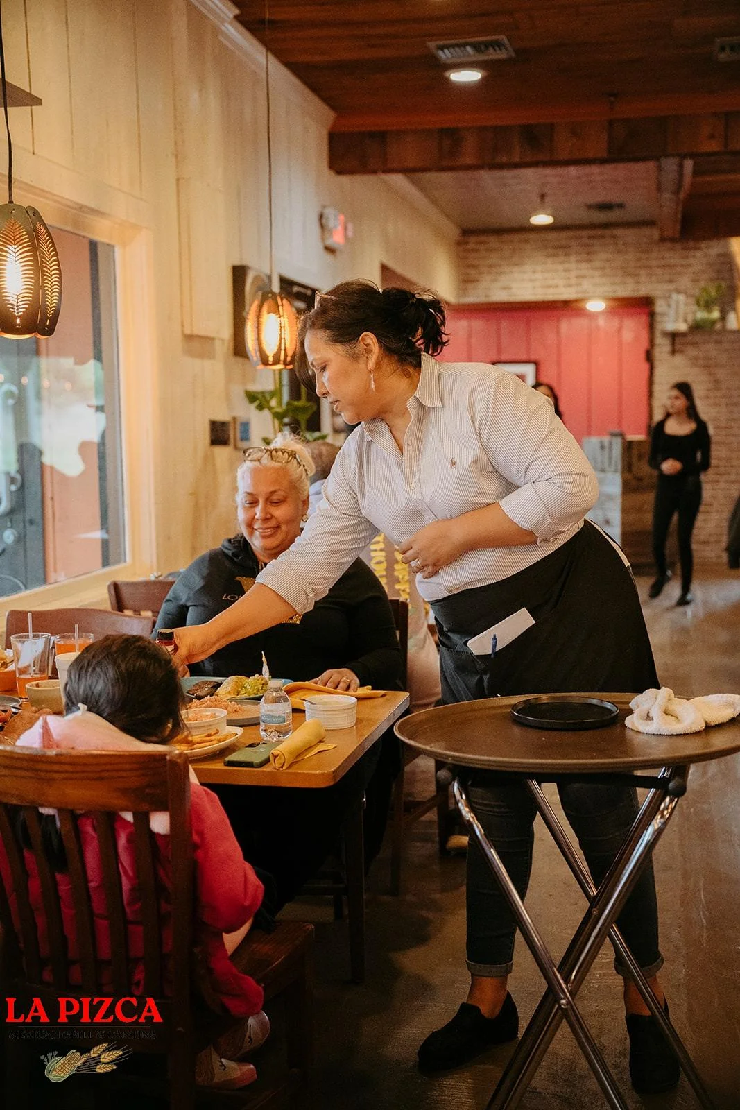 Friendly server attending to diners in a cozy restaurant setting