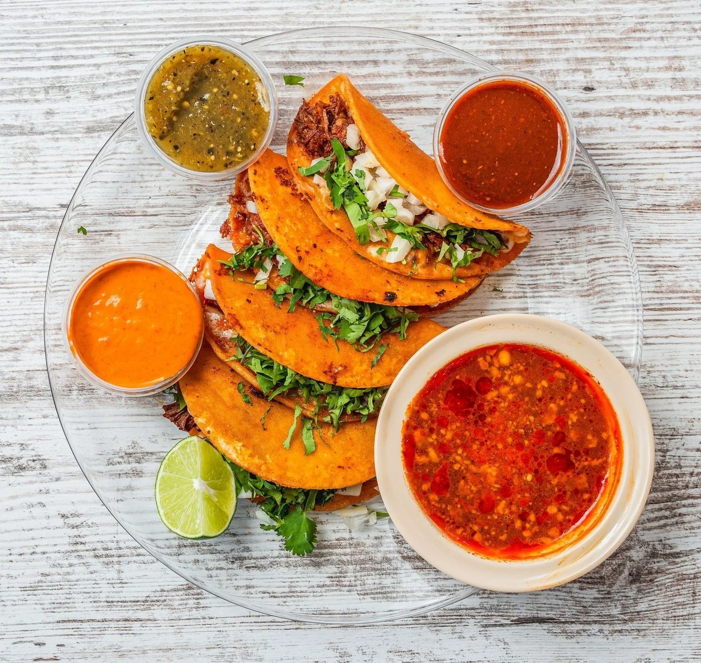 Delicious quesabirria tacos served with broth and garnishes.