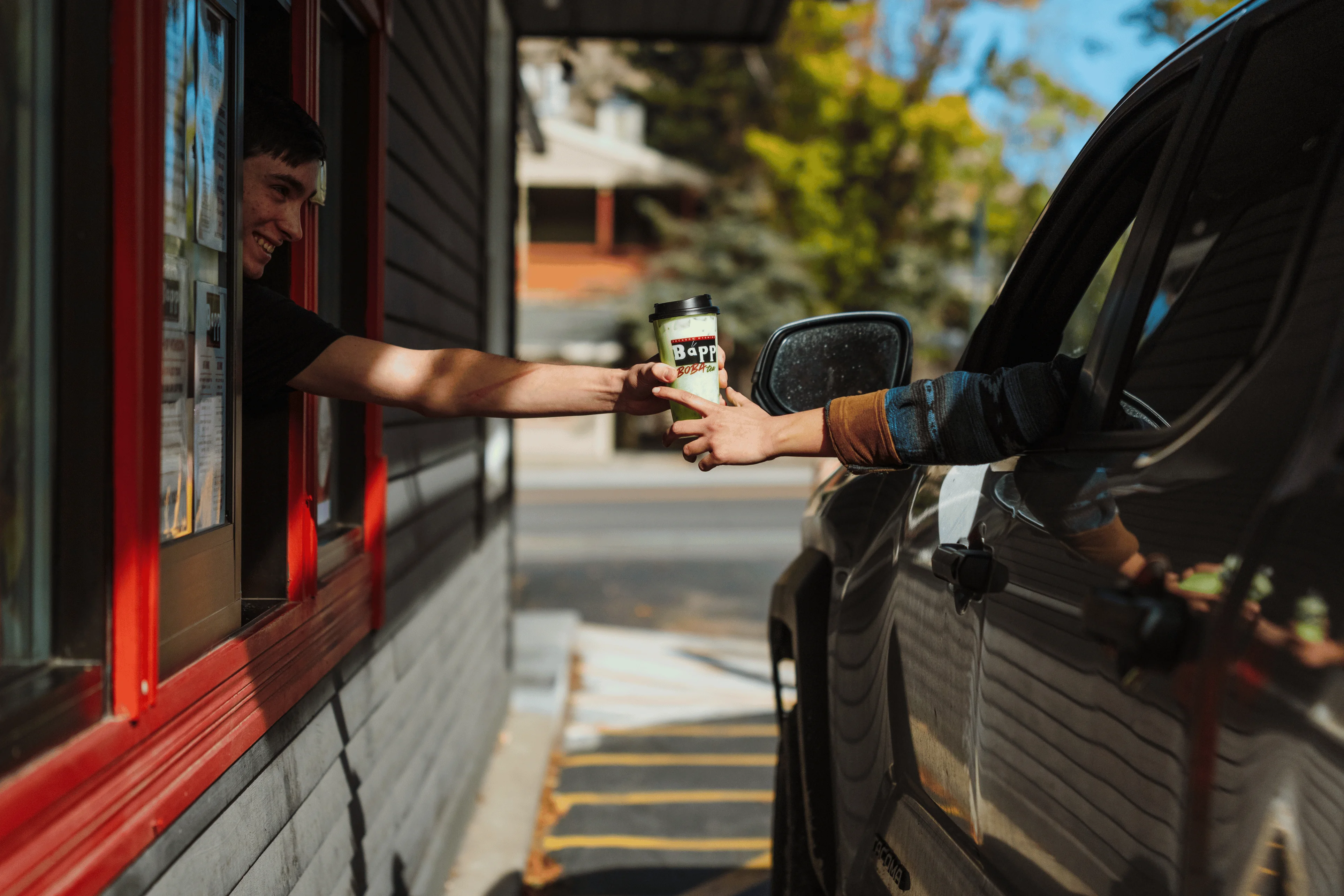 Customer receiving a coffee at a drive-thru window