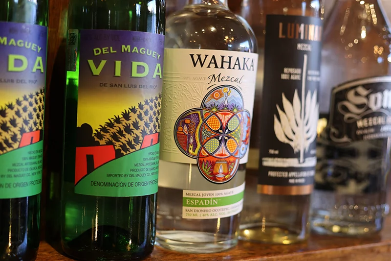 Selection of artisanal mezcal bottles on a wooden shelf