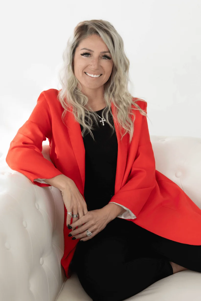 Professional woman in a vibrant red blazer sitting on a white couch