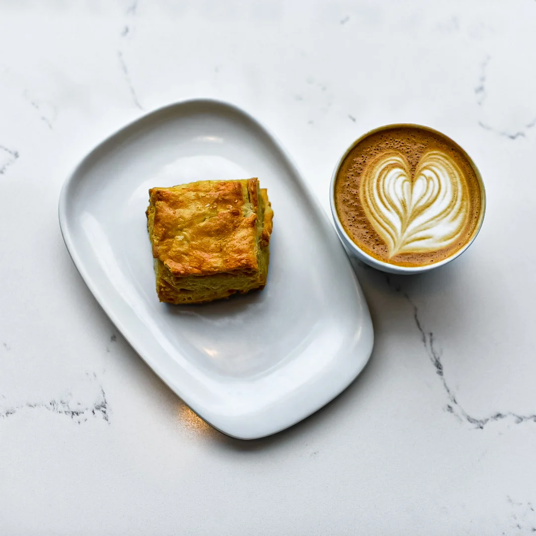 Flaky pastry with coffee art in a cozy café setting