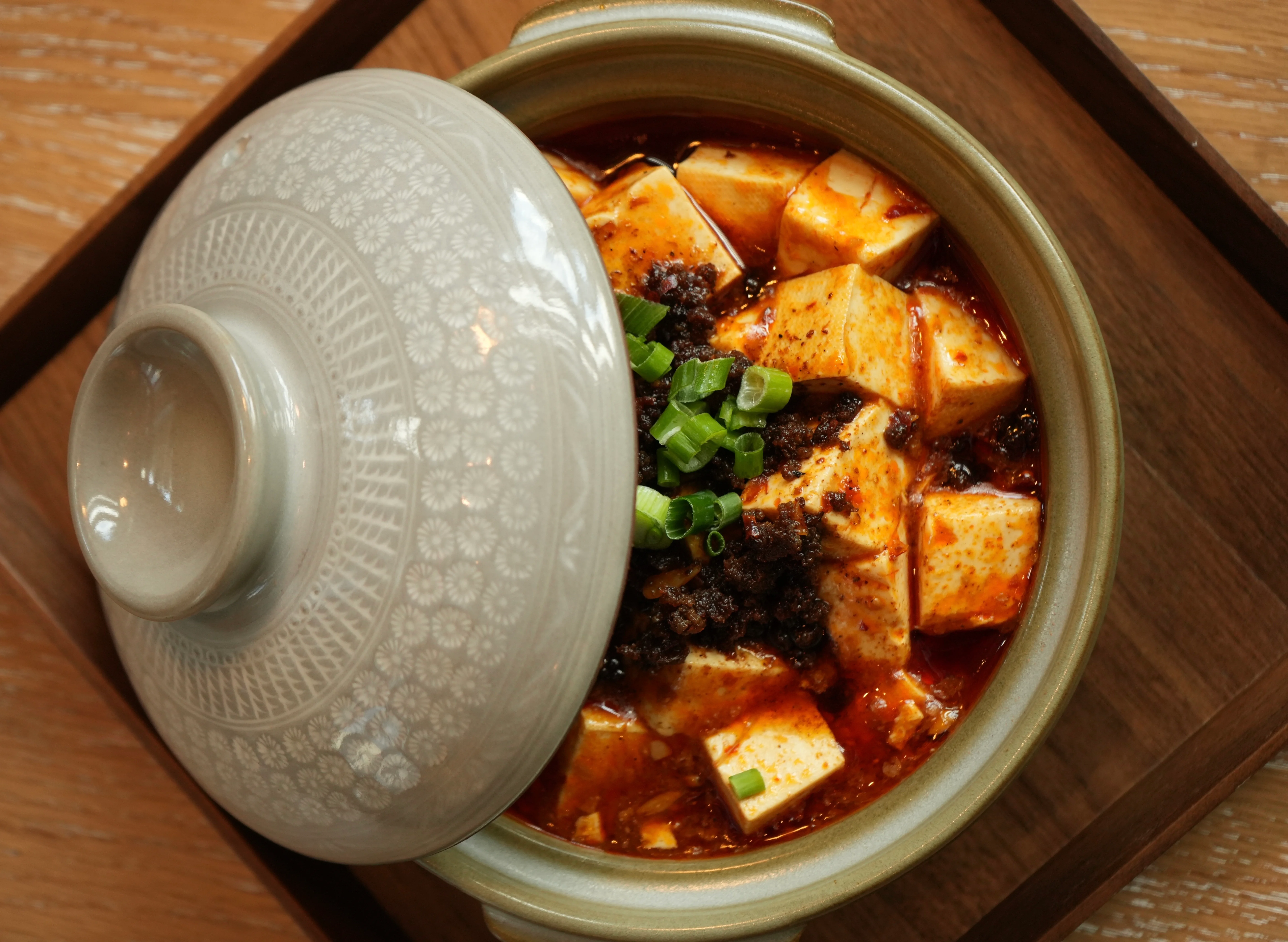 Spicy Sichuan mapo tofu in a clay pot with green onions