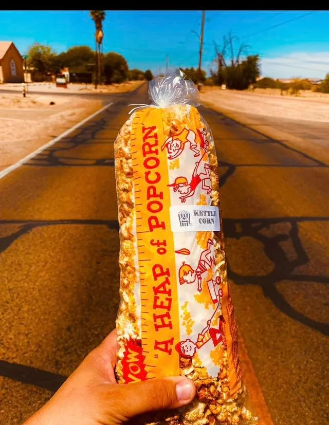 A container of caramel popcorn featuring a playful design with a cheerful character. The popcorn has a glossy caramel coating.