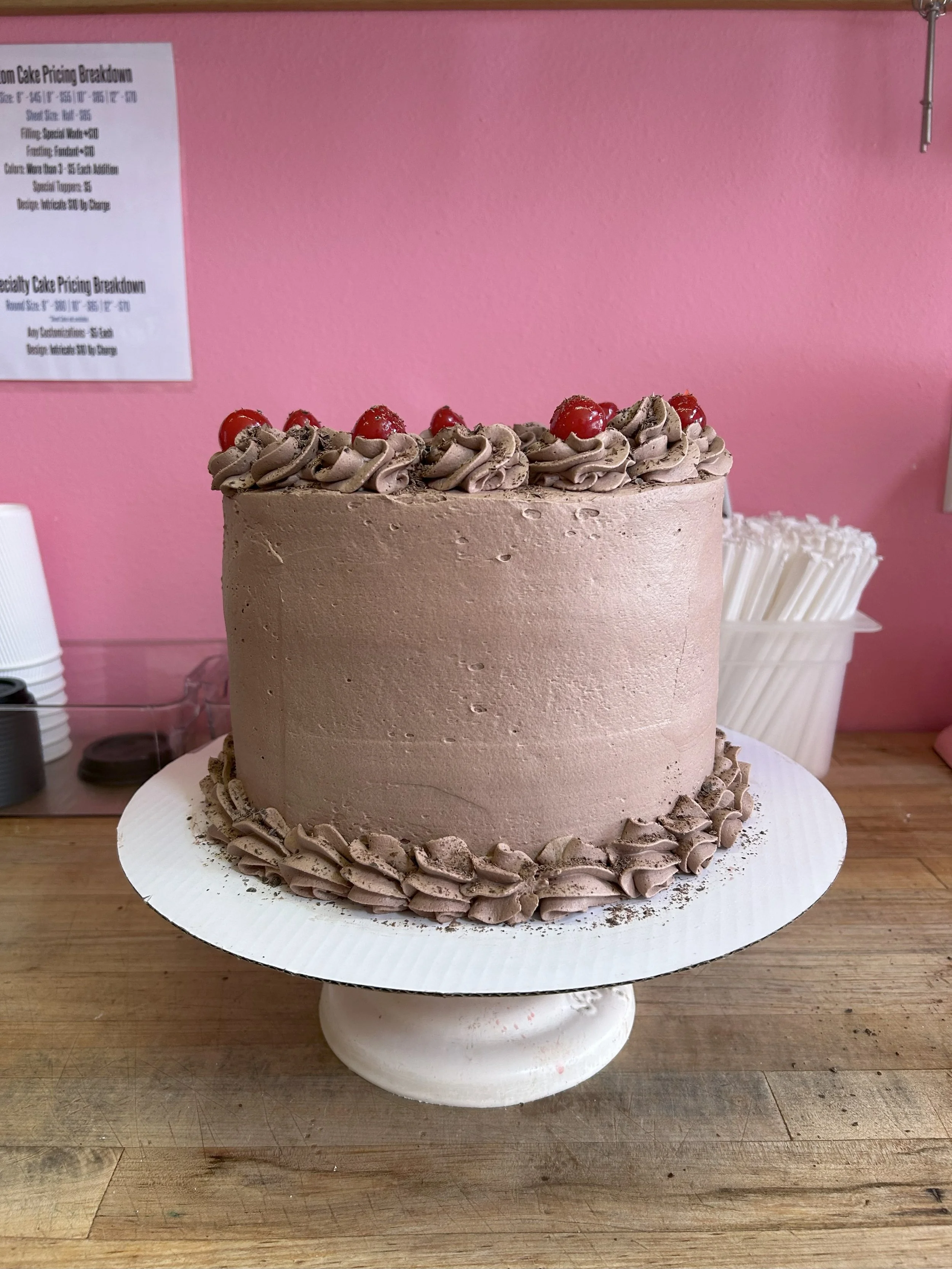 Chocolate layer cake with decorative frosting and cherries