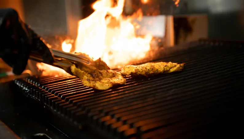 Grilled chicken sizzling on a barbecue with flames