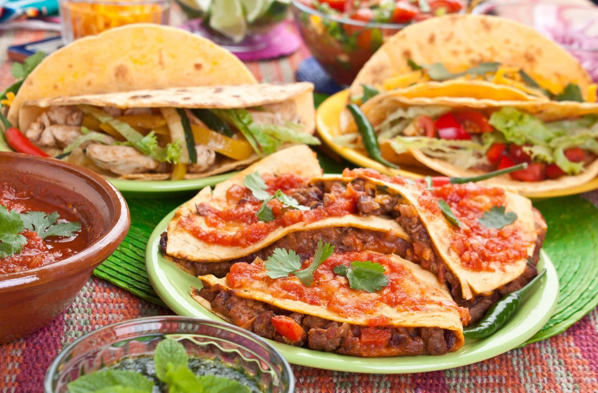 A colorful spread of tacos with salsa and fresh ingredients.