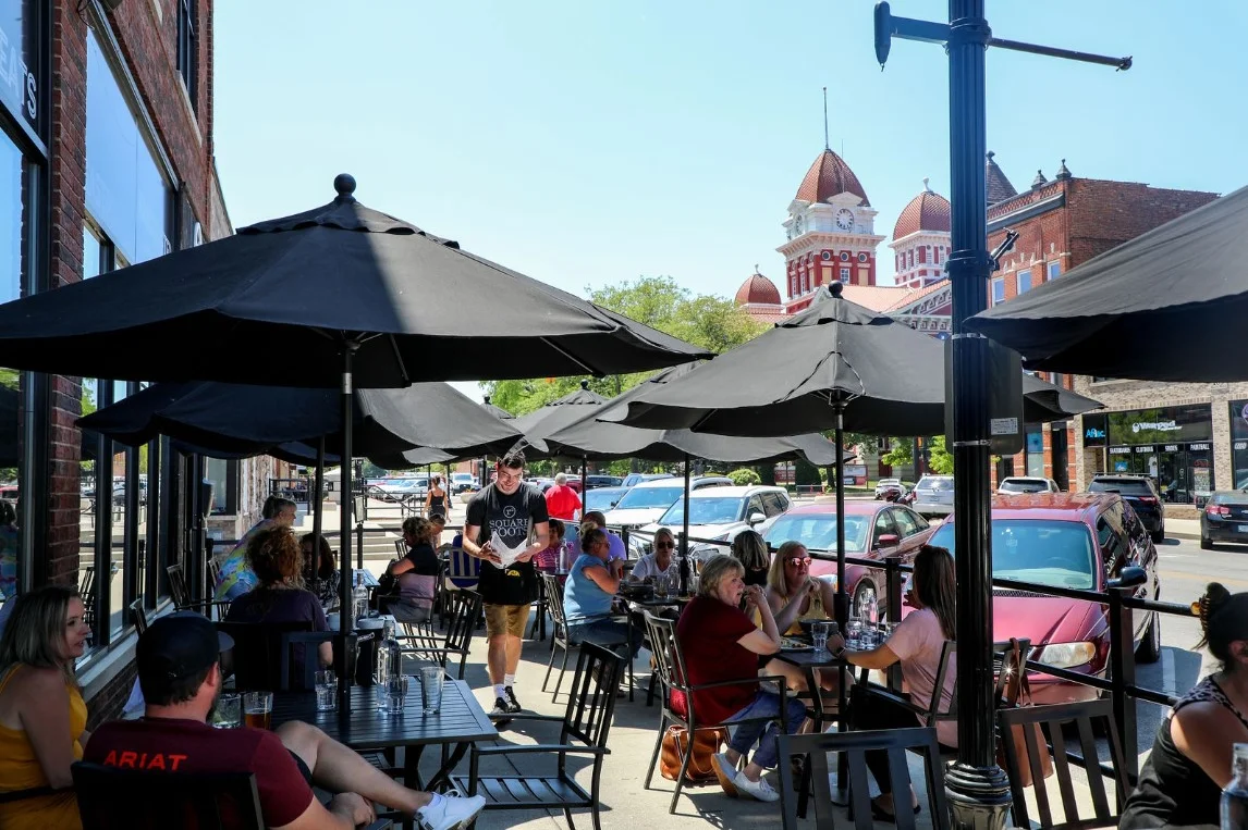 Outdoor dining area with umbrellas and patrons enjoying a sunny day