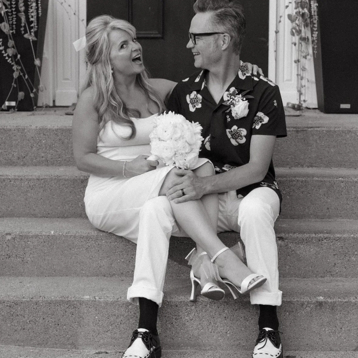 Couple sitting on steps, celebrating their wedding with joy and laughter