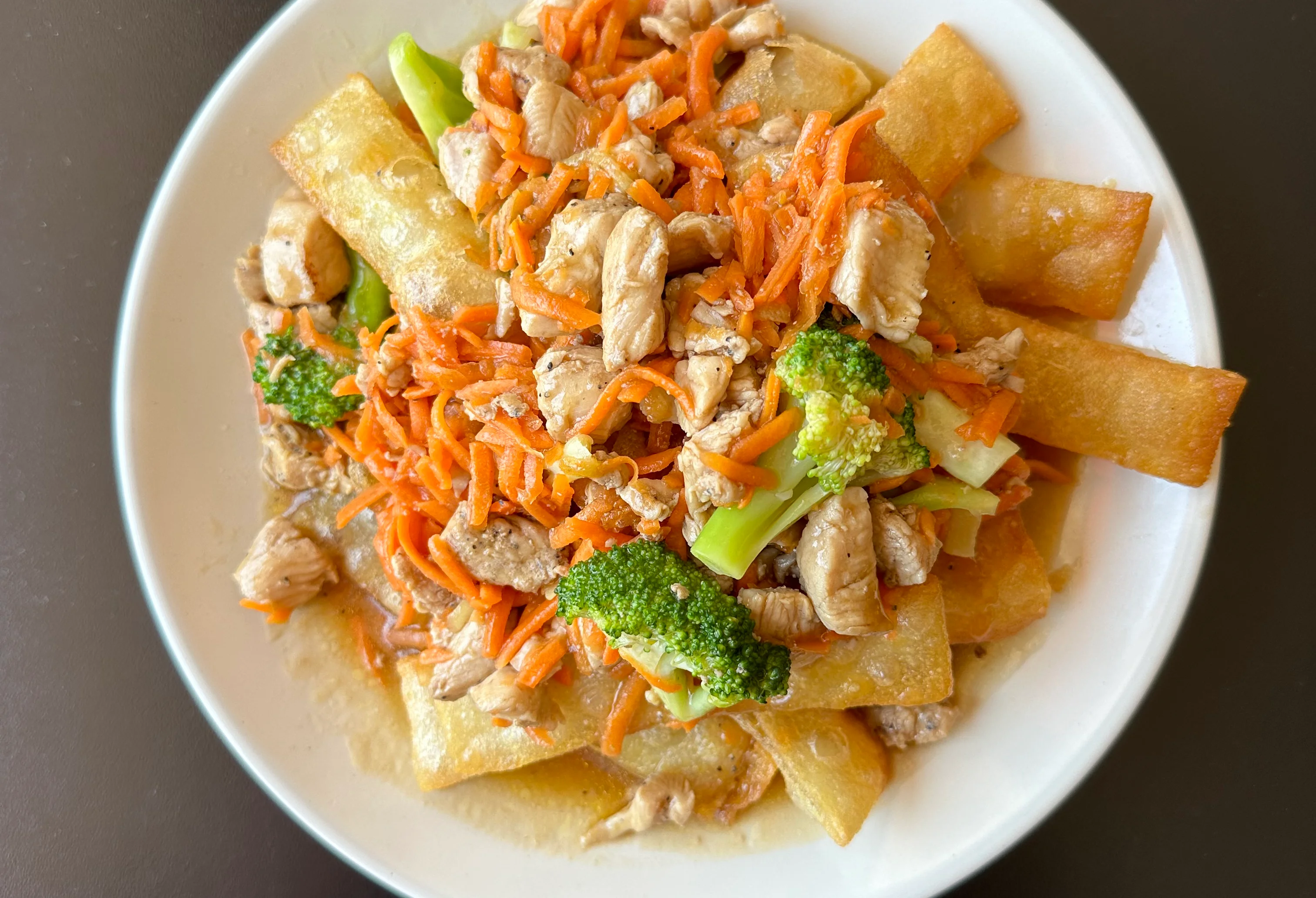 Stir-fried chicken with broccoli and carrots on crispy noodles