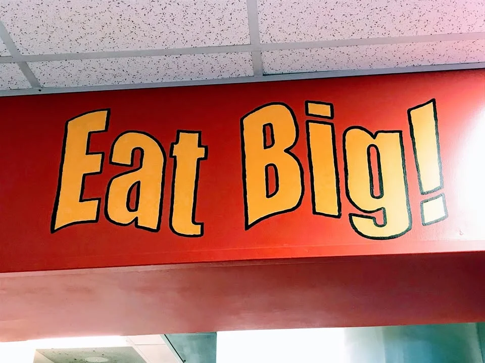 Restaurant sign encouraging diners to enjoy large portions