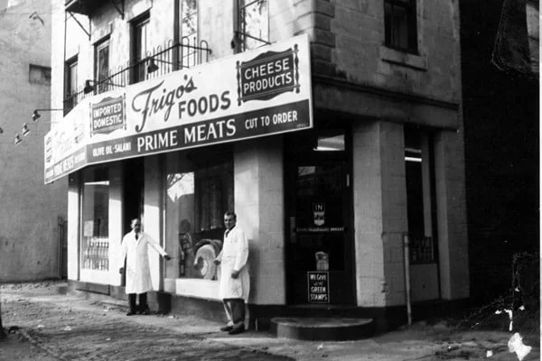 Historic butcher shop exterior with signage and two men in white coats