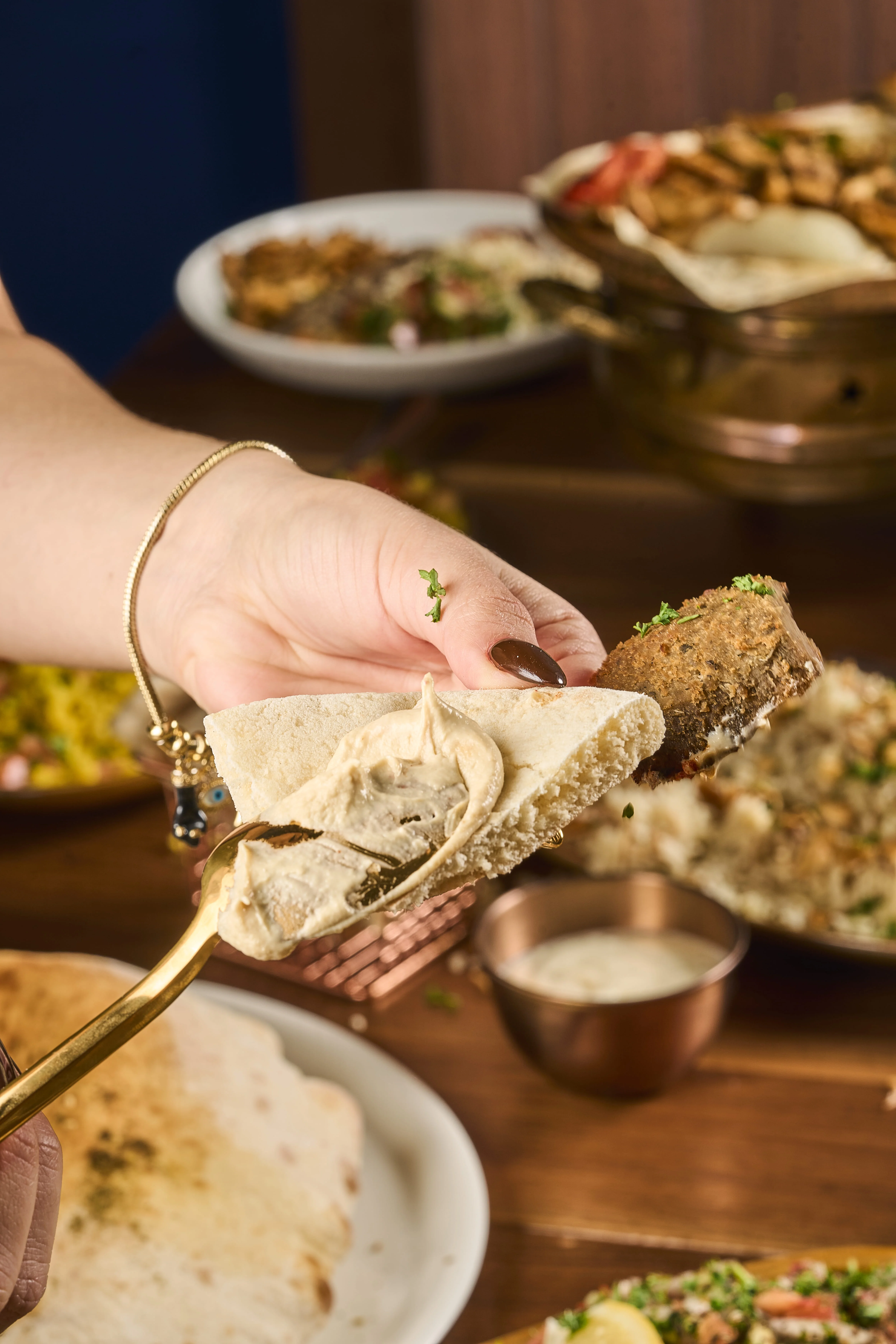 Hummus being spread on a pita bread. 