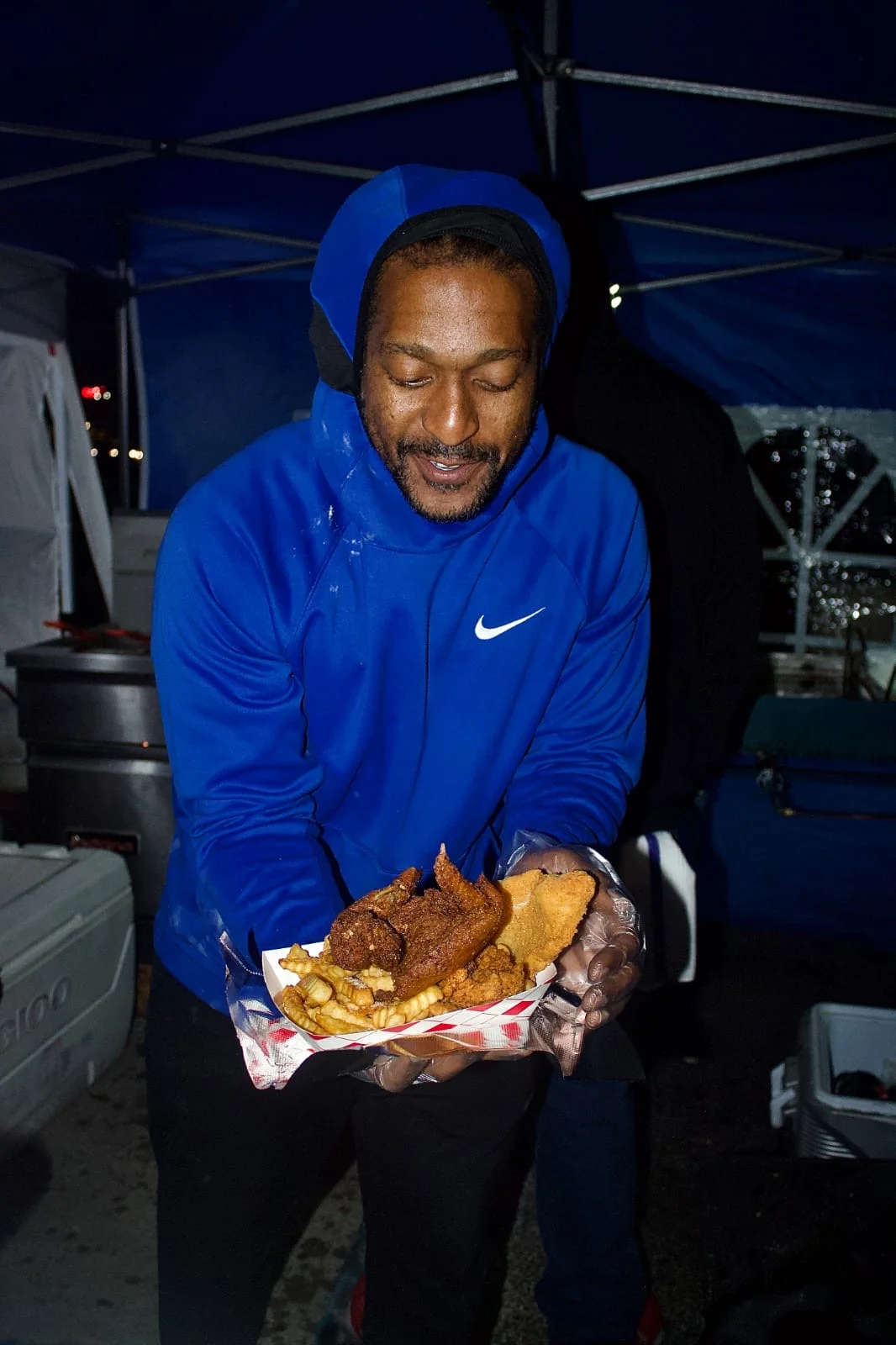 Itean Dozier in his signature blue color serving fried chicken and fries under the DOZ DHR blue tent
