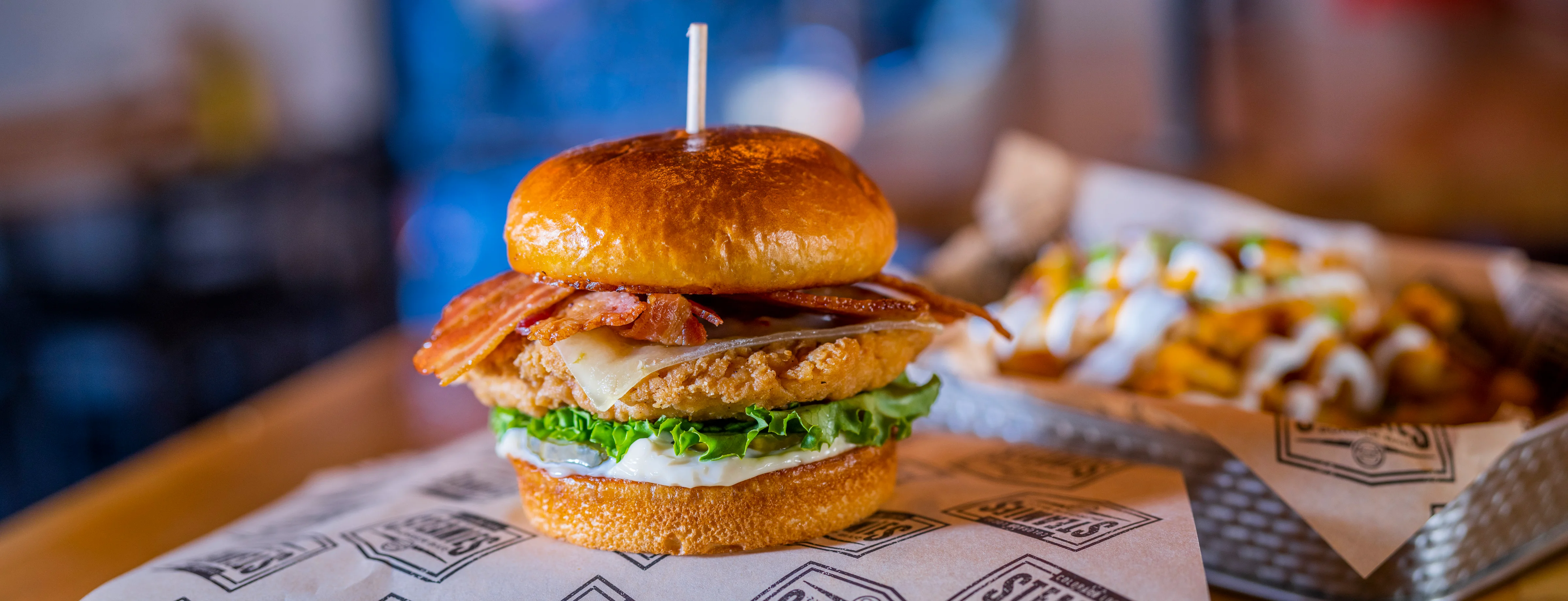 A gourmet burger featuring a brioche bun, a juicy beef patty, melted cheese, and fresh lettuce. It’s beautifully arranged on a wrapper.