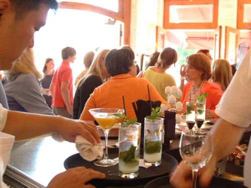 Bartender serving cocktails at a lively bar during a social gathering