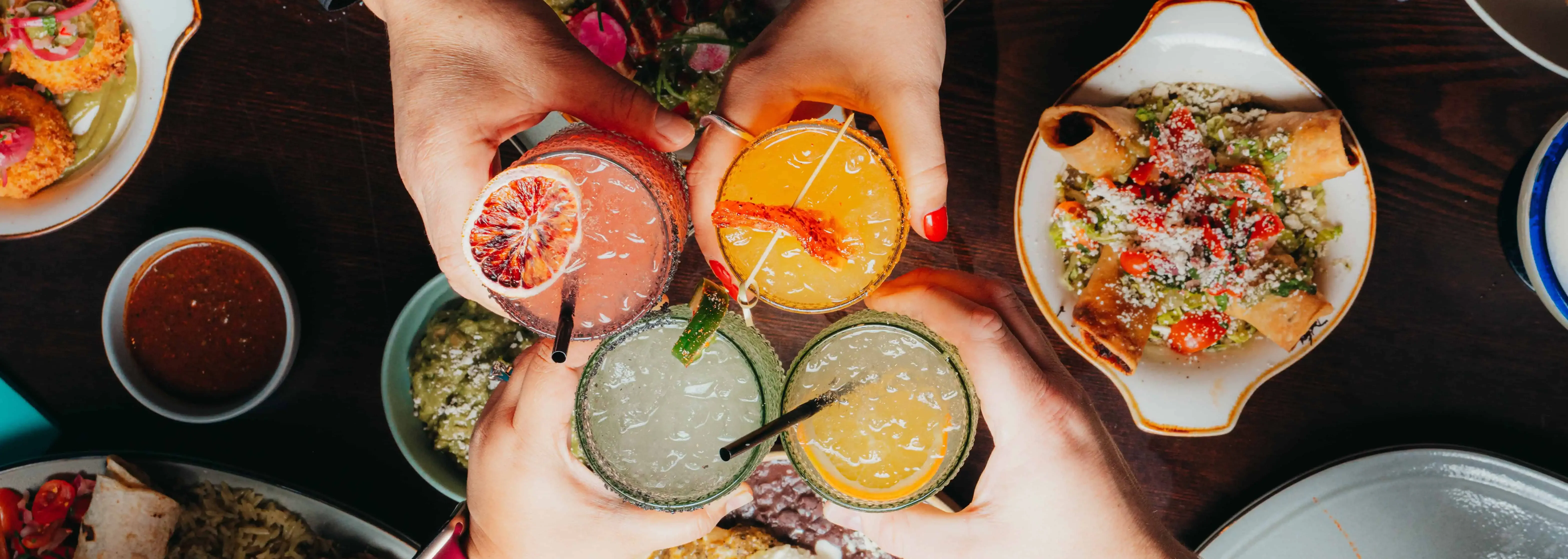 Colorful cocktails clinking over a vibrant Mexican feast