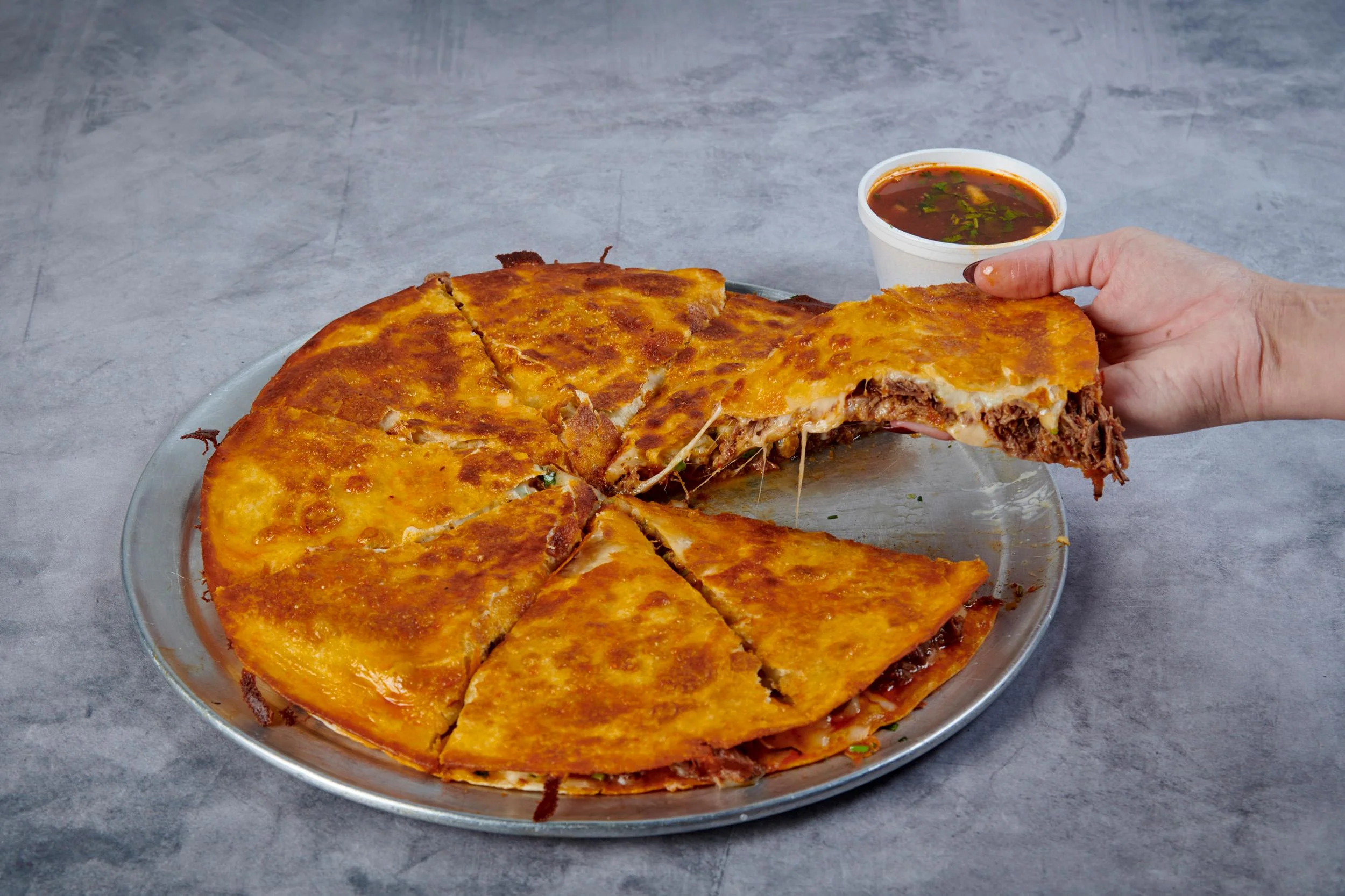 Birria pizza with melted cheese and consommé at Fuego Cravings