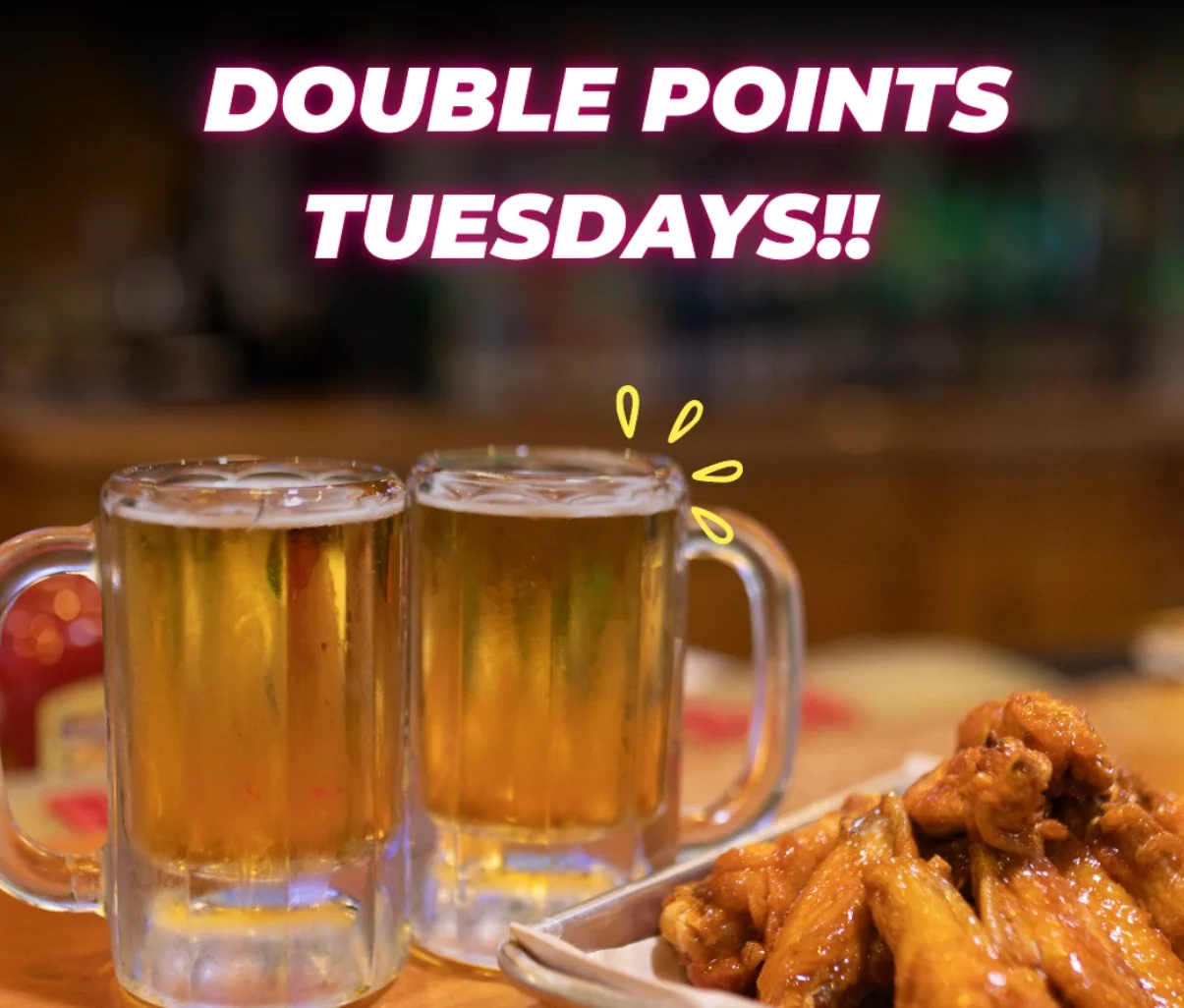 Two beers and wings sitting on a bar table