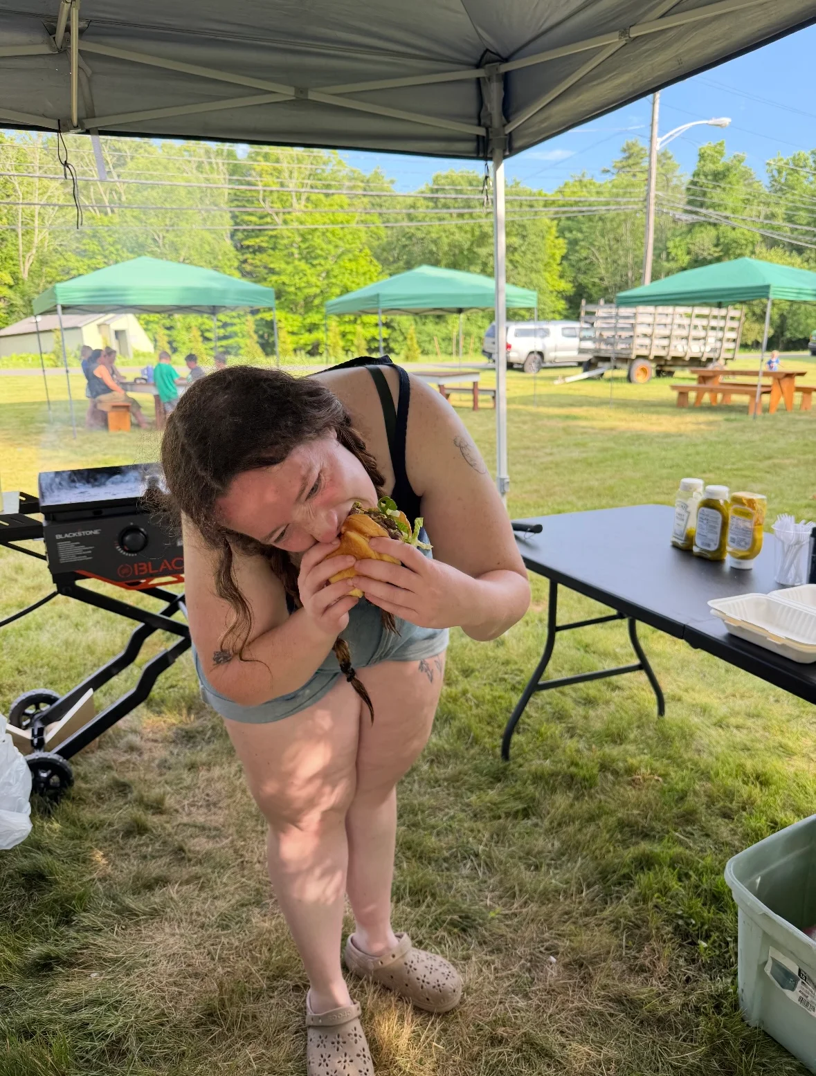 Person enjoying a juicy hamburger at an outdoor event