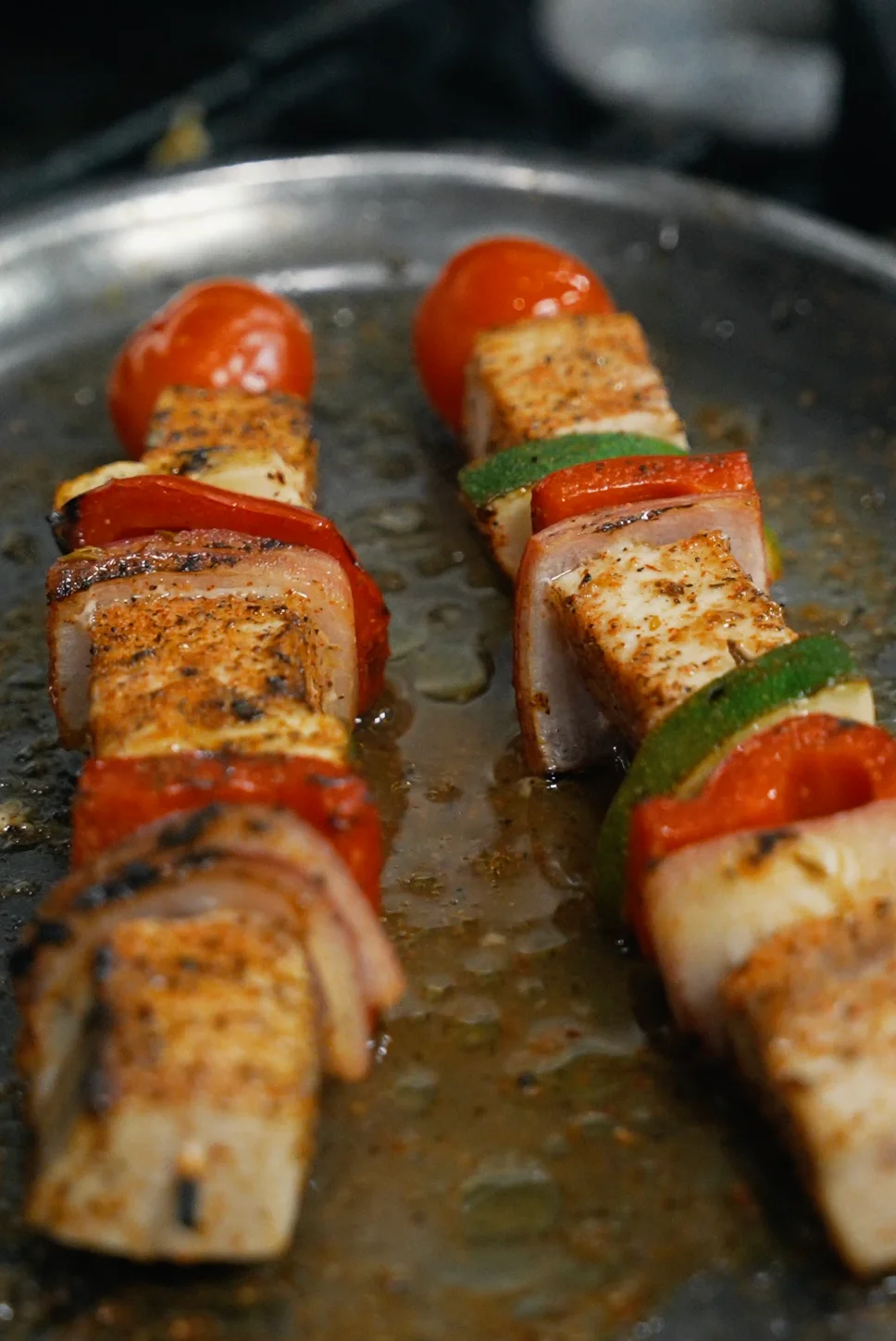Grilled vegetable and tofu skewers on a metal platter.