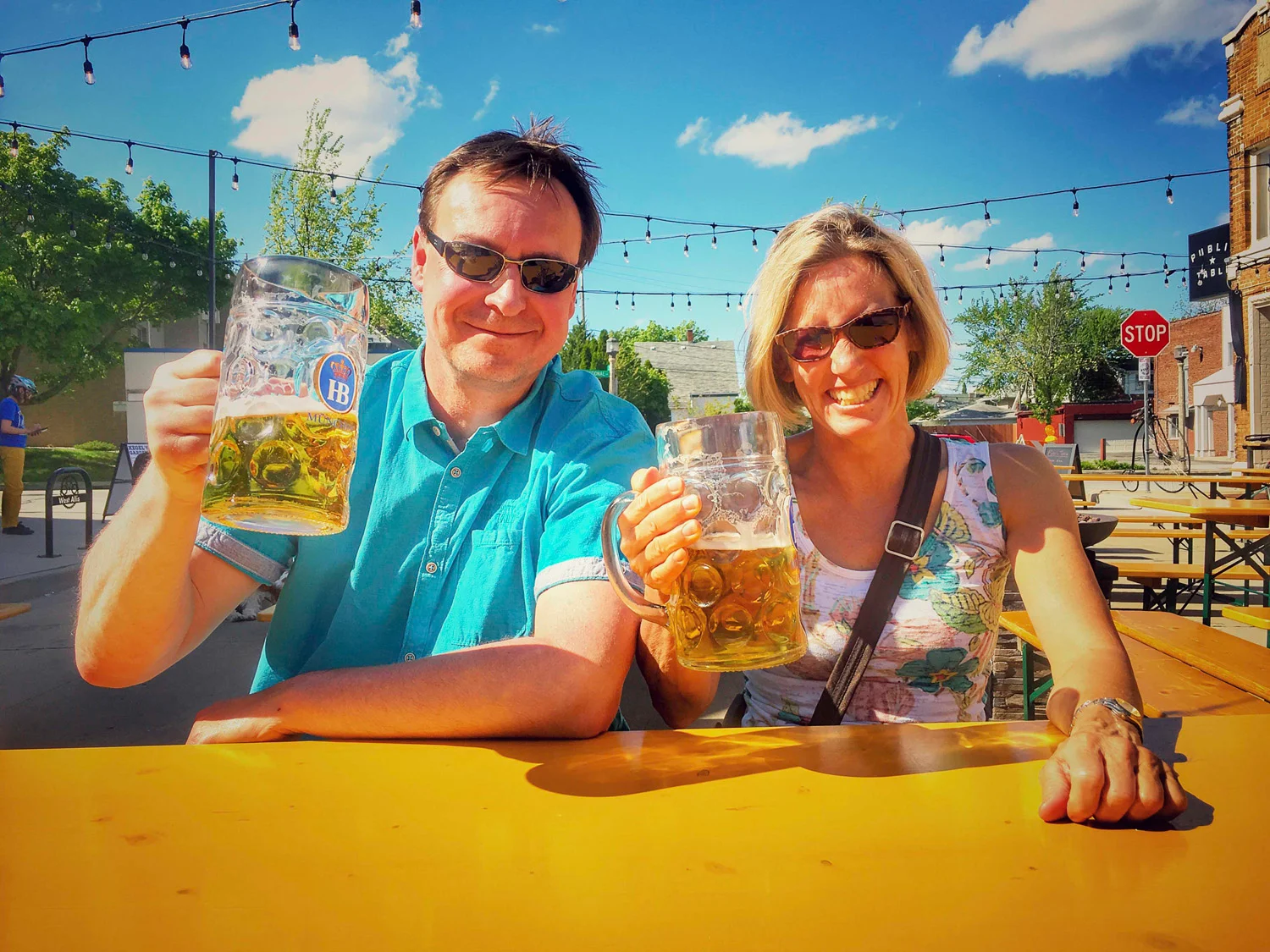 Two friends toasting with large beer mugs outdoors