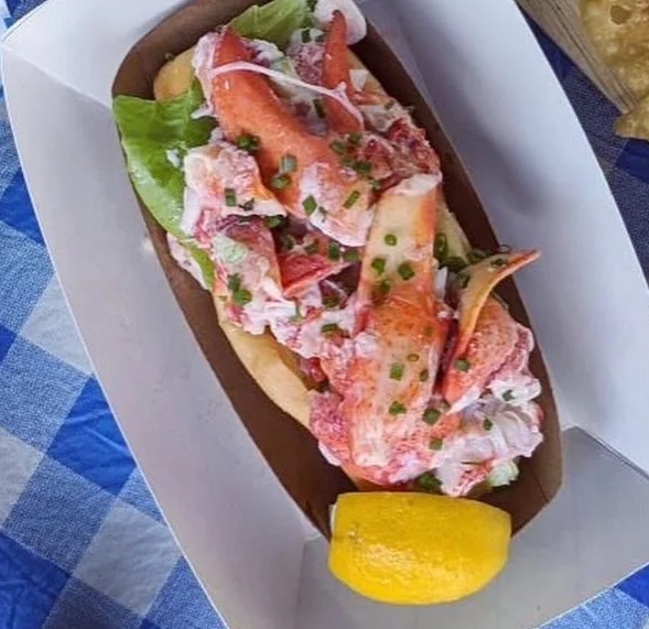 Lobster roll served with lemon on a picnic table