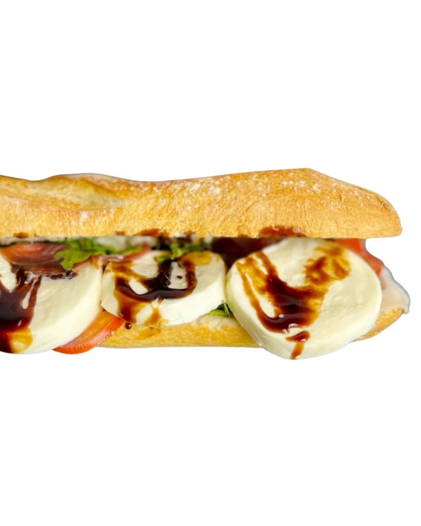A baguette sandwich filled with fresh mozzarella, tomatoes, and a drizzle of balsamic glaze for added flavor.
