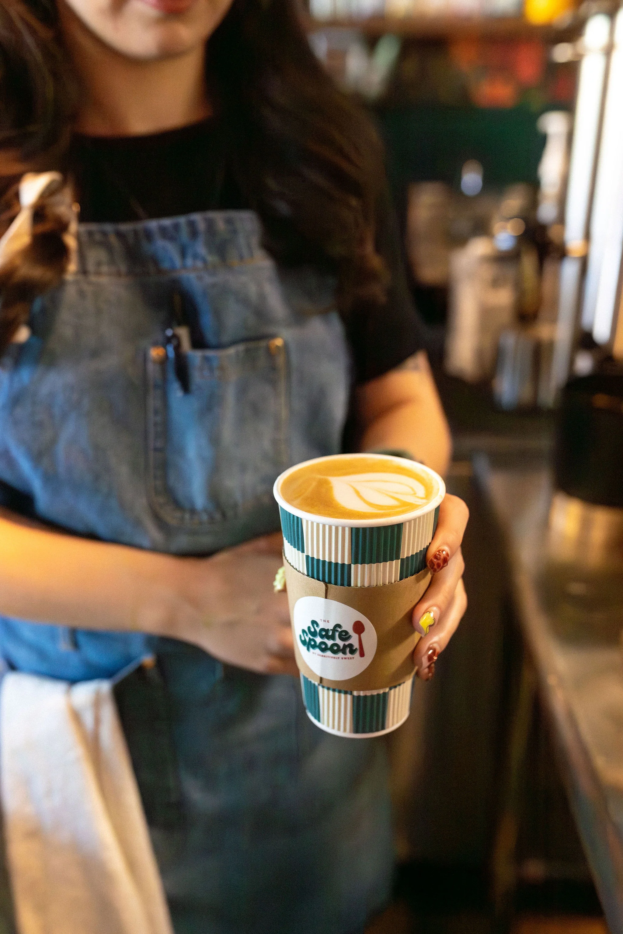 Barista holding a latte art coffee in a café