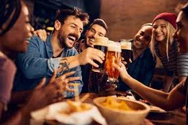 Group of friends toasting with beers in a lively bar setting