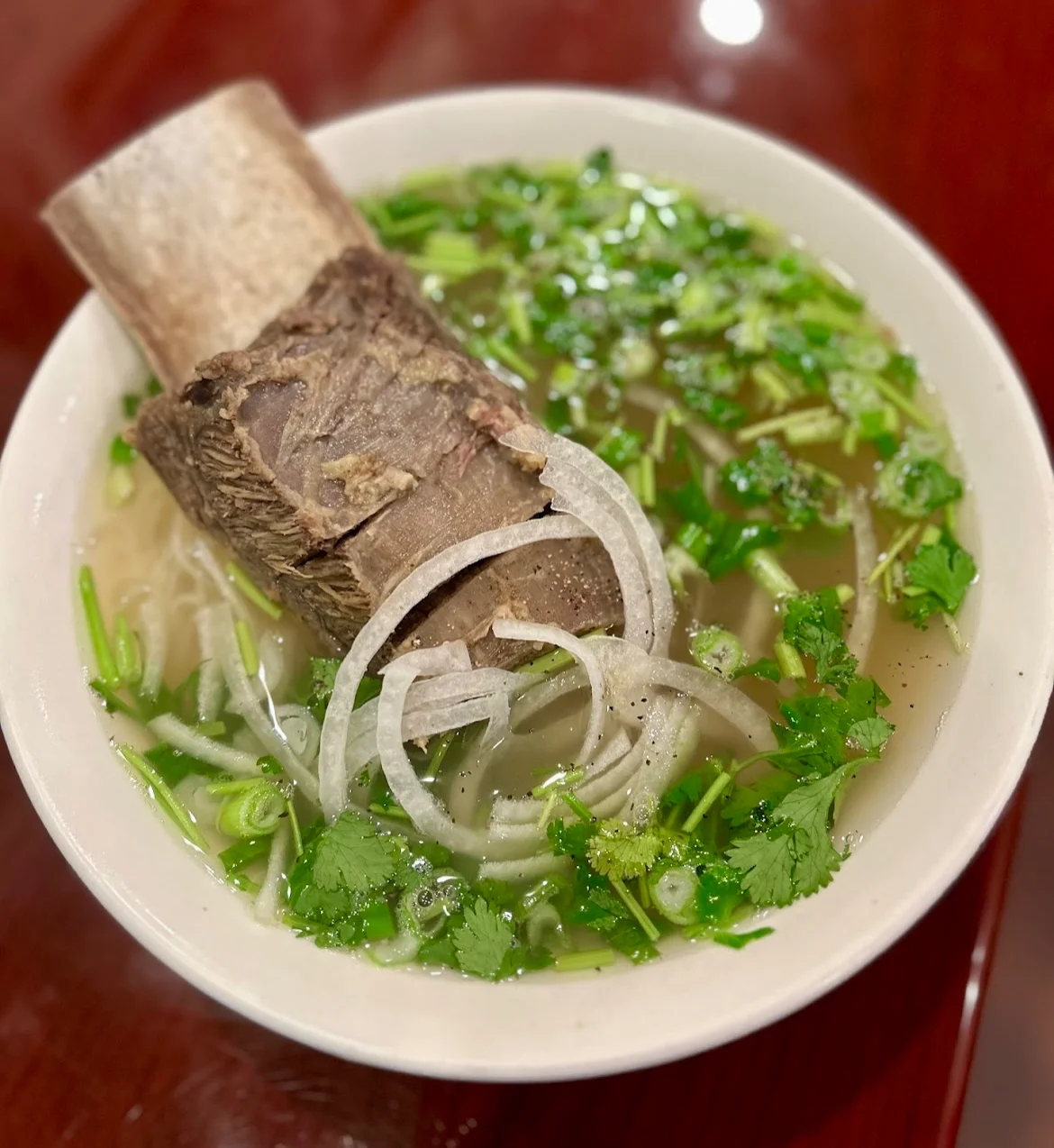 Bowl of Vietnamese pho with beef bone and fresh herbs