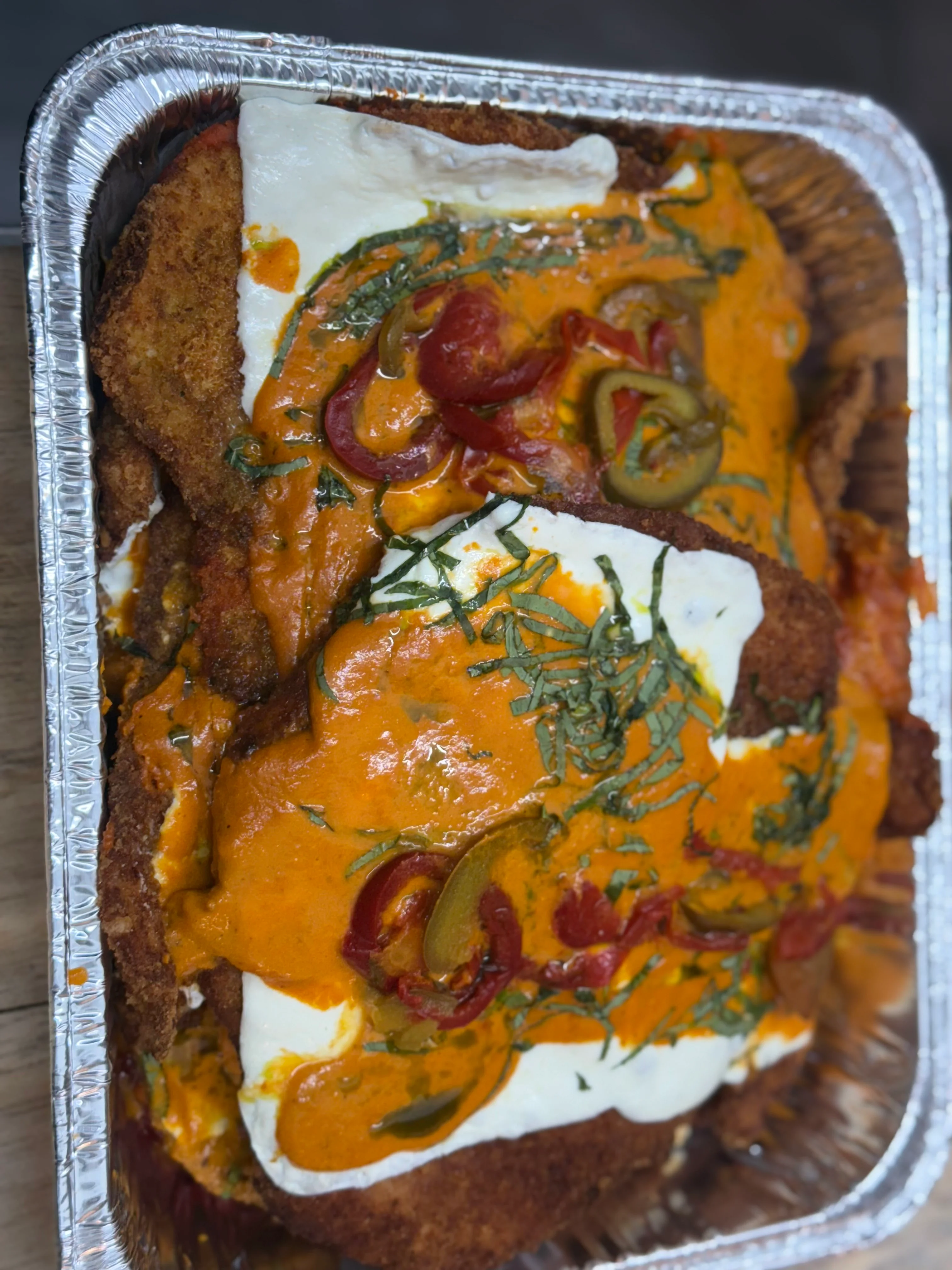 Crispy chicken parmesan with marinara sauce and fresh herbs