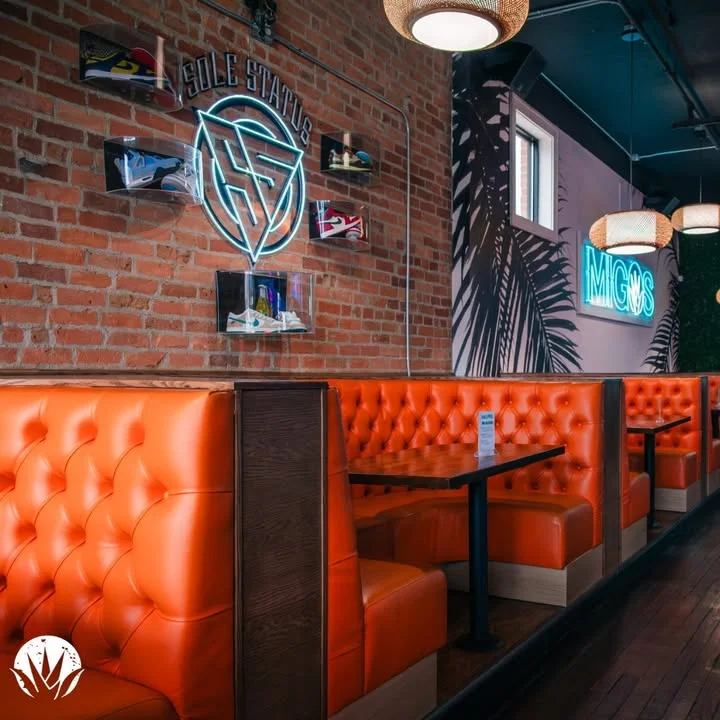 Trendy restaurant interior with orange booths and neon signage