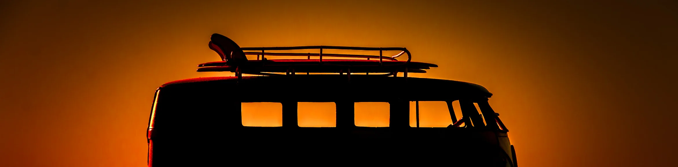 Silhouette of a vintage van against a sunset backdrop