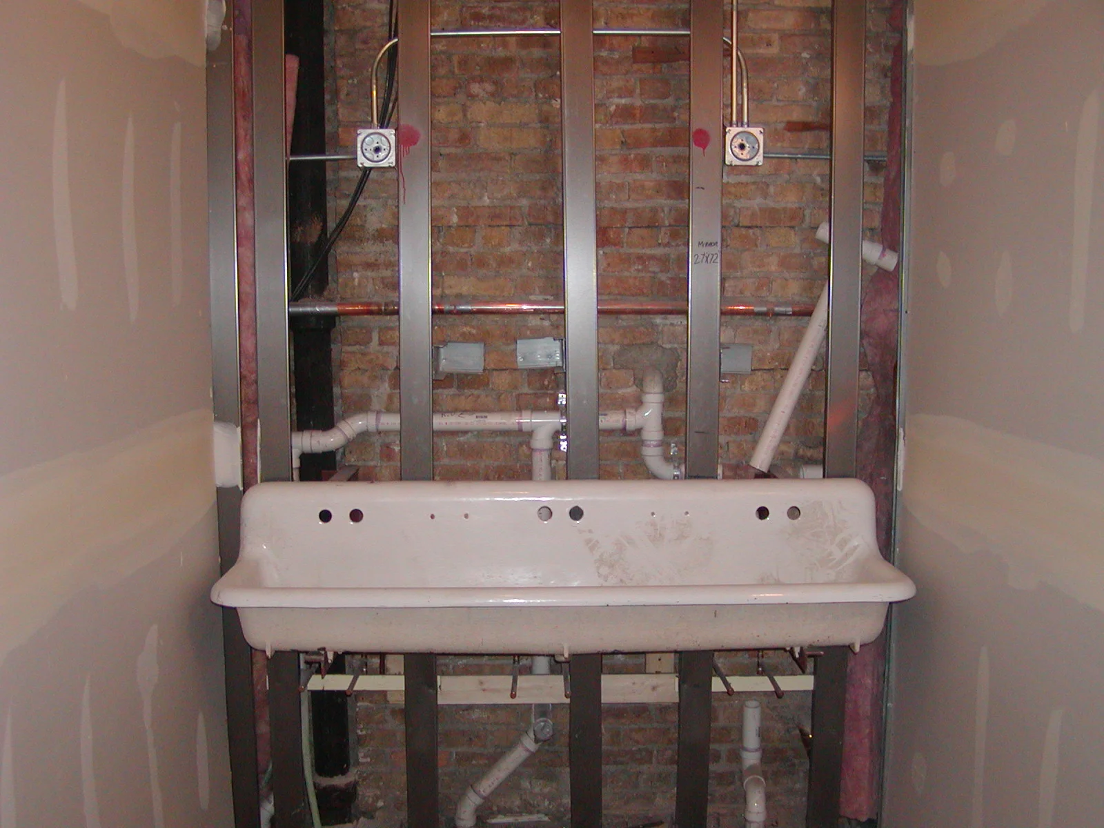 Exposed plumbing and sink installation in a renovation project