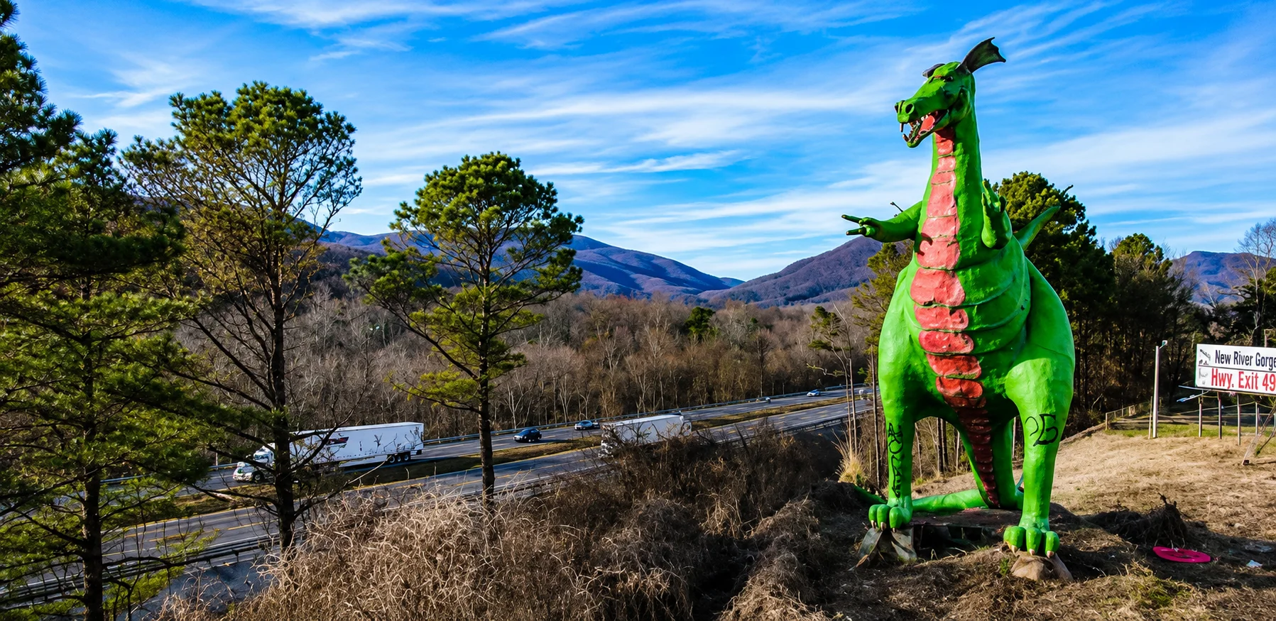 Colorful dragon statue overlooking a highway and mountains.