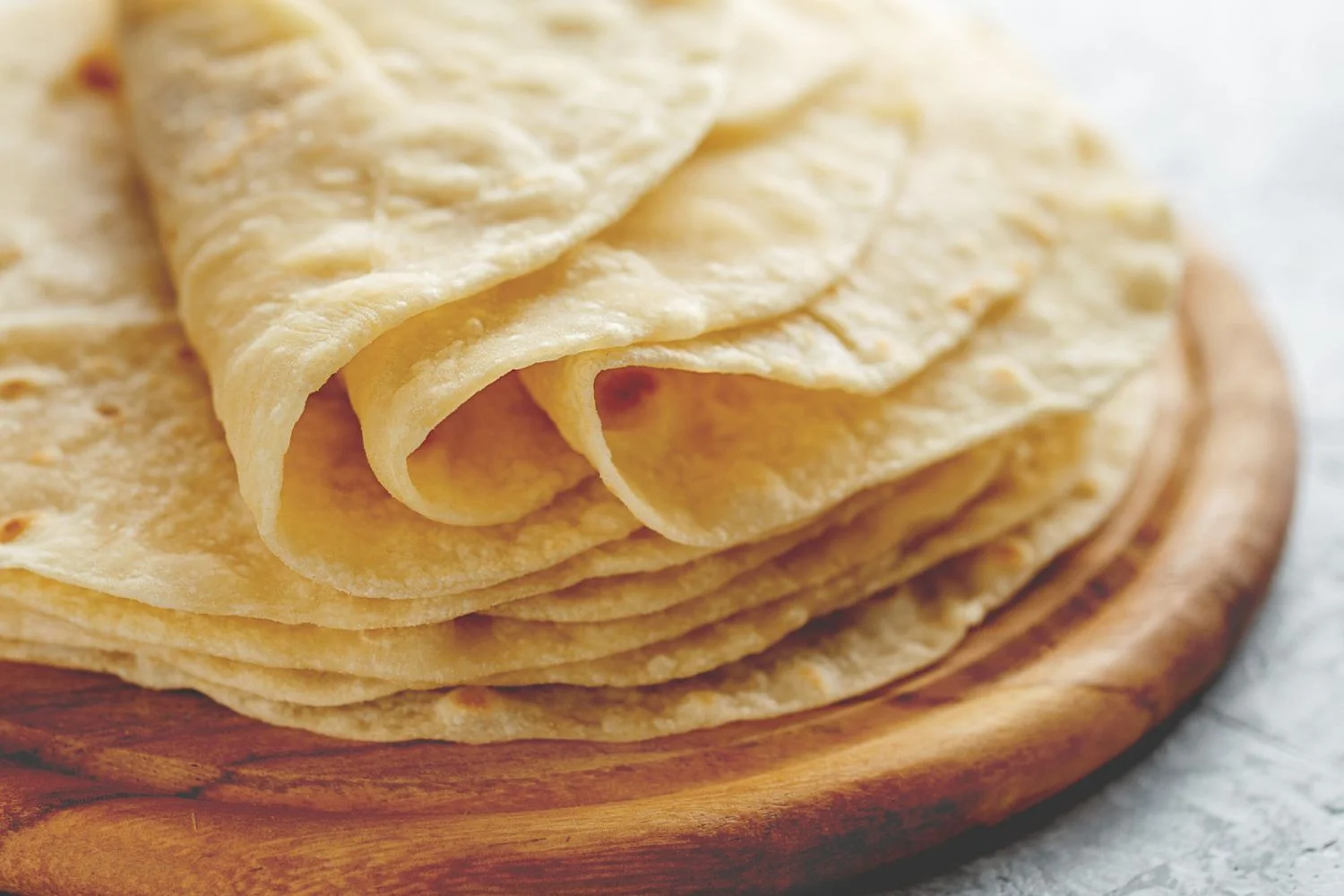 Freshly made tortillas stacked on a wooden board