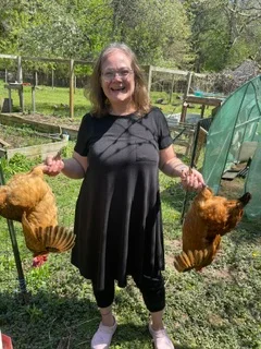 Woman joyfully holding two chickens in a backyard garden