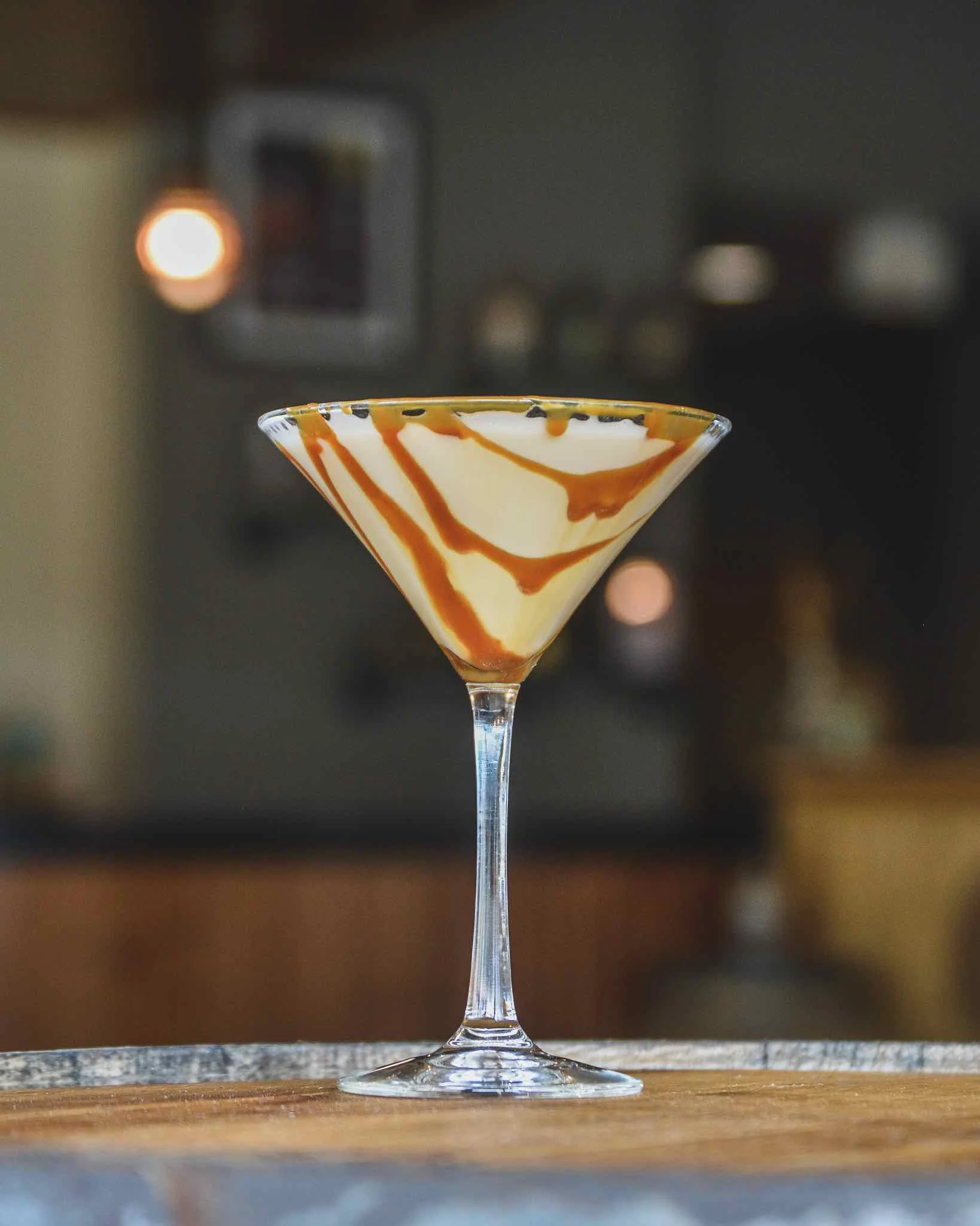 Spiked Hazelnut Martini on a table with lights glowing in the background