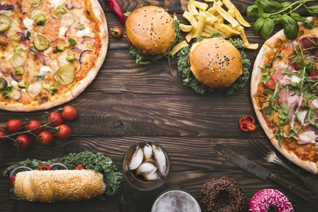 Delicious spread of pizzas, burgers, and fries on a rustic wooden table